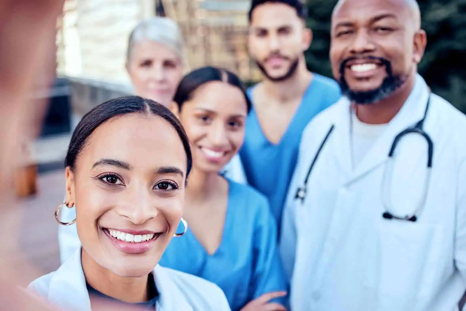 A diverse group of medical professionals providing personalized care, smiling, with a young woman taking a selfie in the foreground.